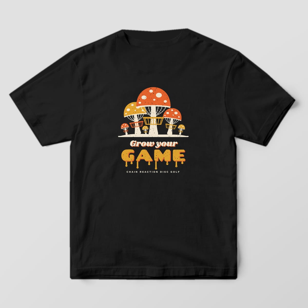 Back of a Black Comfort Colors 1717 tee printed with orange and mustard spotted mushrooms built like disc golf baskets above the words Grow your GAME in melting letters.