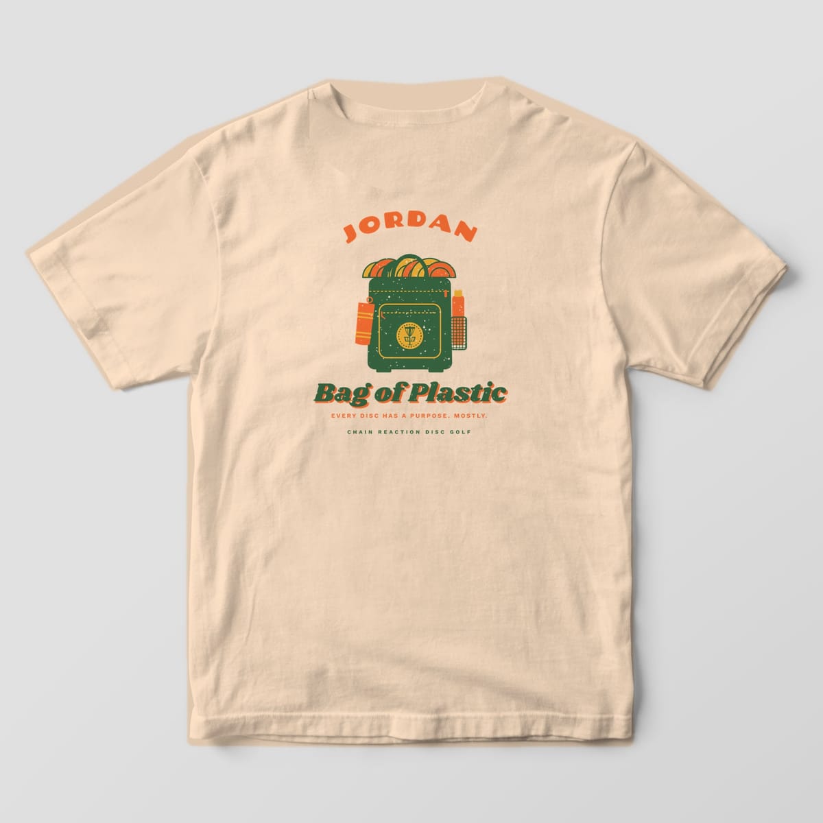 Back of an Ivory Comfort Colors 1717 tee printed with a custom name arched over a green disc golf backpack stuffed with orange and mustard discs above the words Bag of Plastic.