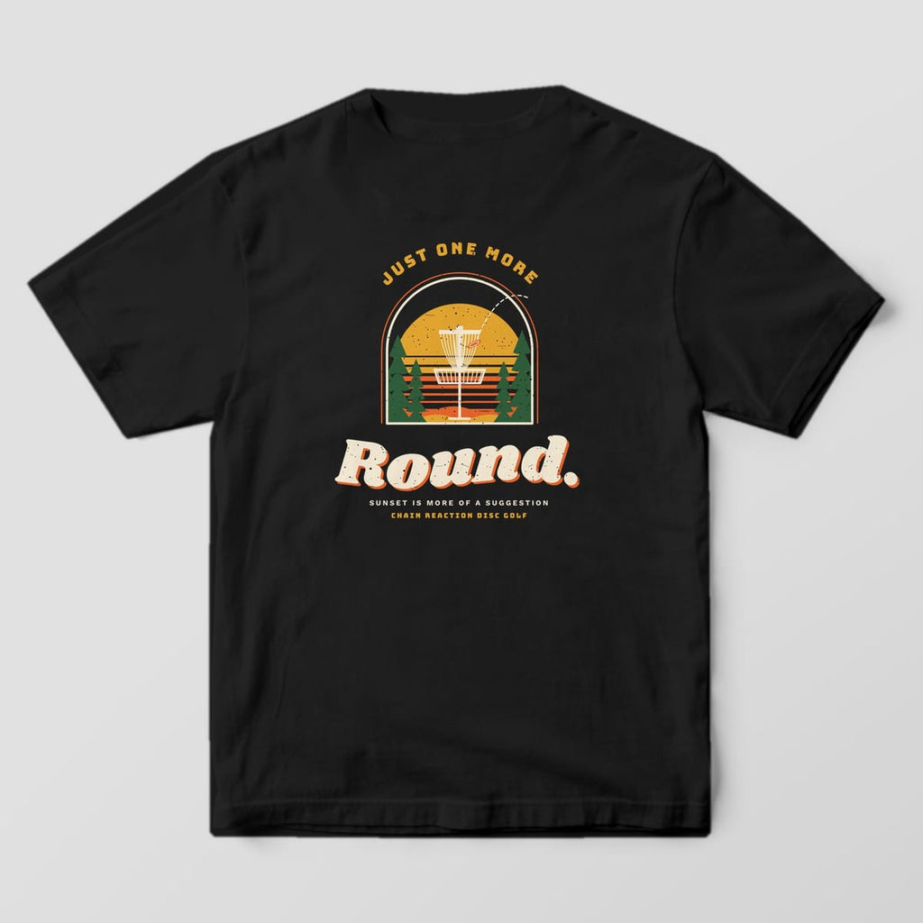 Back of a black Comfort Colors t-shirt with a disc golf basket in front of a striped sunset and the words Just One More Round