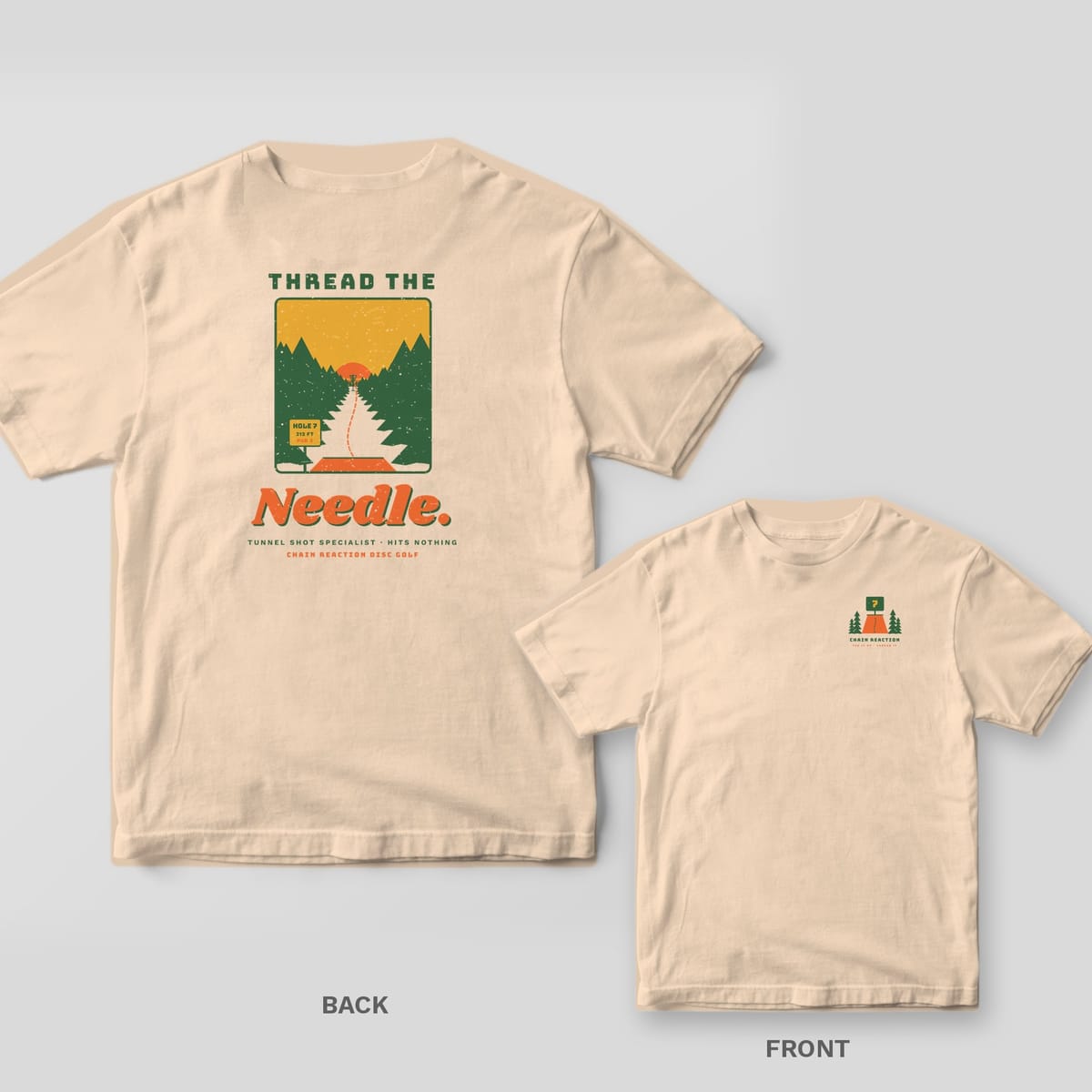 Ivory t-shirt shown back and front: tee pad view down a tunnel of green pines to a distant basket and sun, Thread the Needle lettering, small tee pad logo on chest