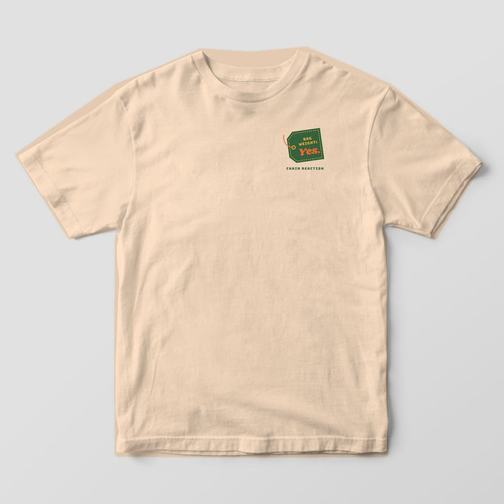 Front of an ivory Comfort Colors t-shirt with a small green luggage tag reading Bag Weight: Yes