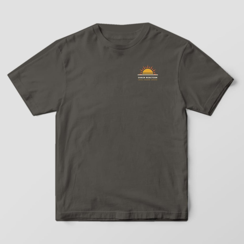 Front of a pepper Comfort Colors t-shirt with a small rising sun logo and Chain Reaction text