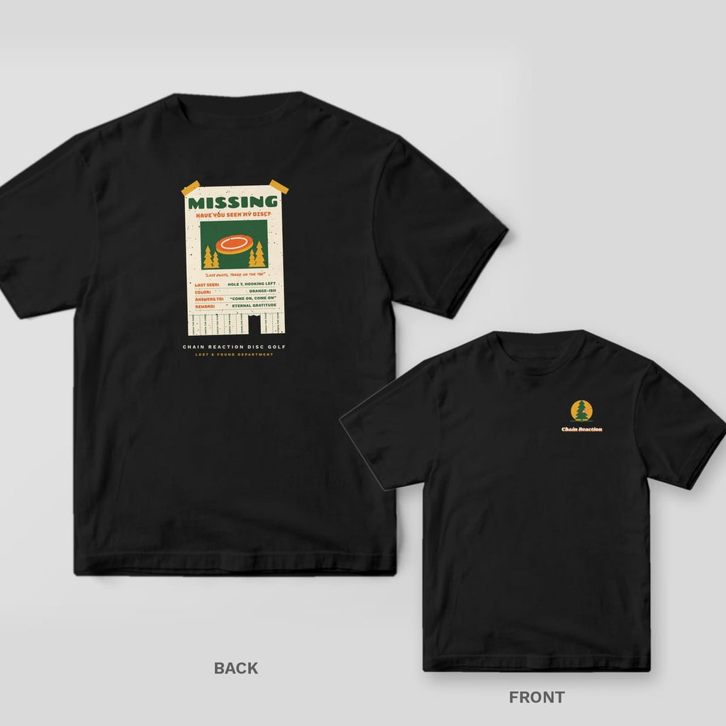 Black Comfort Colors tee shown back and front: a cream taped-up Missing poster with a photo of an orange disc, lost-disc details and tear-off tabs on the back, a small pine tree with a disc stuck in it and the Chain Reaction wordmark on the chest.
