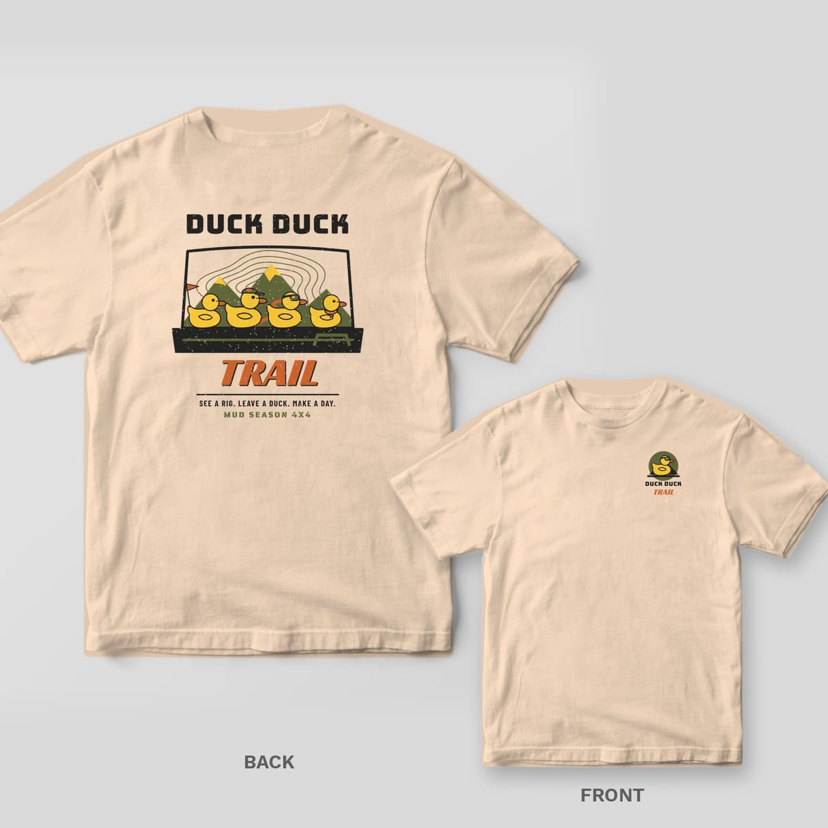 Ivory Comfort Colors 1717 tee shown back and front: four rubber ducks on a dashboard with mountains behind and Duck Duck Trail text on the back, rubber duck badge reading Duck Duck Trail on the left chest