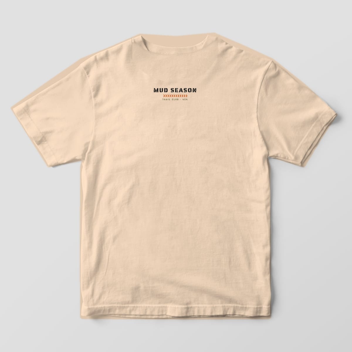 Back of an ivory Comfort Colors 1717 T-shirt with a small Mud Season stencil mark and tread strip below the collar.