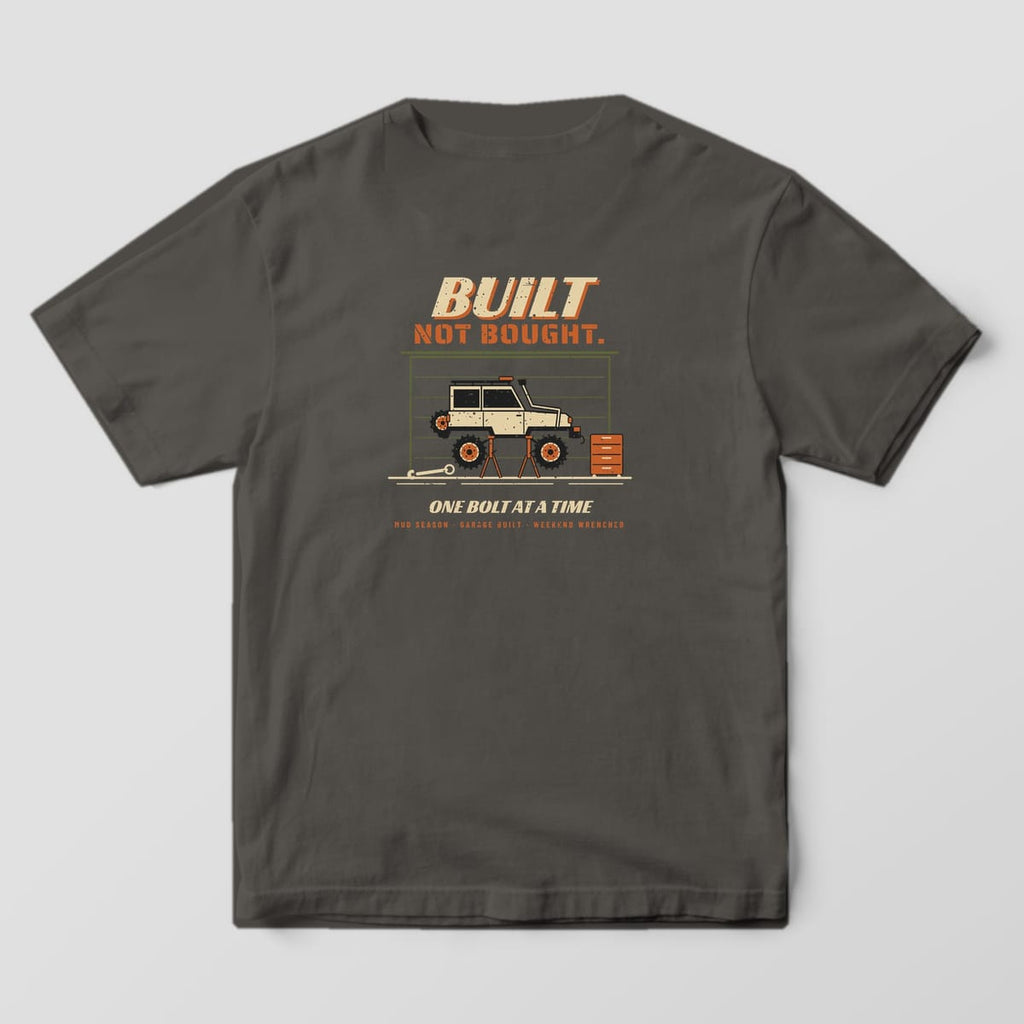 Back of a pepper Comfort Colors 1717 T-shirt printed with a lifted 4x4 on jack stands in a garage and Built Not Bought lettering.