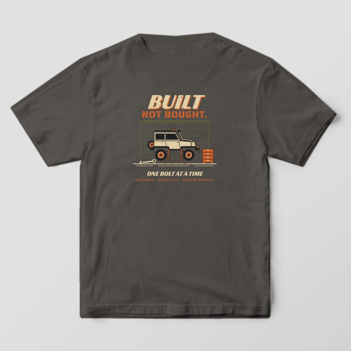 Back of a pepper Comfort Colors 1717 T-shirt printed with a lifted 4x4 on jack stands in a garage and Built Not Bought lettering.