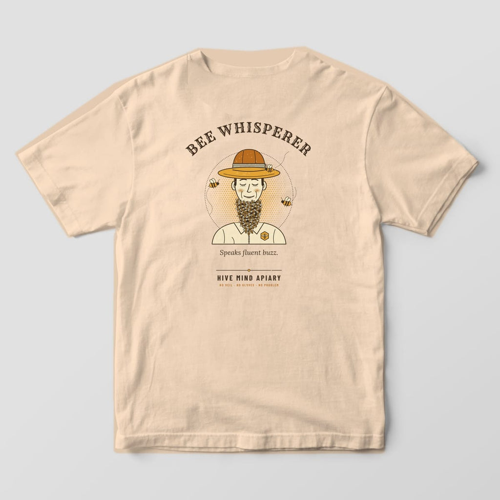 Back of an ivory Comfort Colors 1717 T-shirt printed with a retro portrait of a smiling beekeeper with a beard made of bees, titled Bee Whisperer.