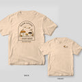 Back and front of an ivory Comfort Colors T-shirt; the back shows an arch-framed cottage scene of mushrooms, ferns and a snail with bees zooming overhead, titled Slow Living Fast Bees, the front has a small mushroom and bee left-chest print.
