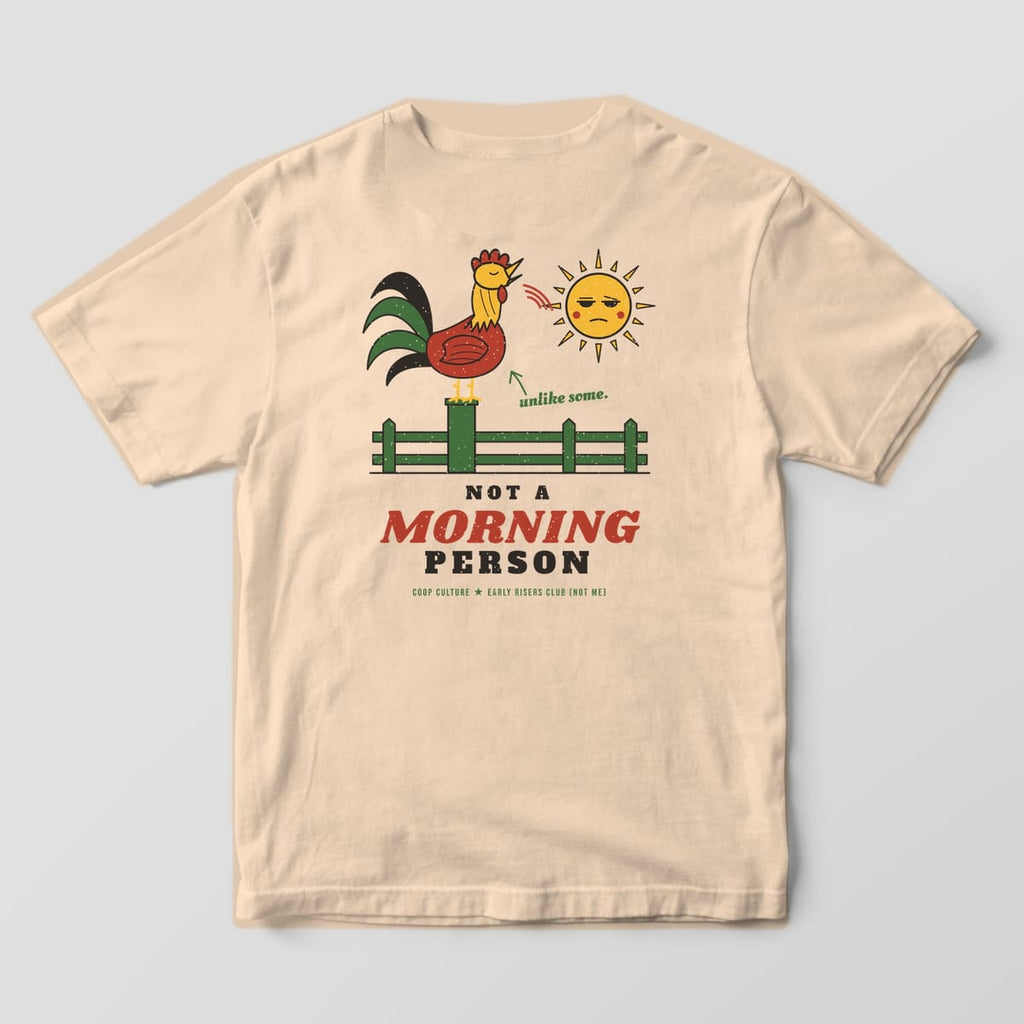 Back of an ivory Comfort Colors 1717 tee with a crowing rooster on a fence post, a sleepy sun and Not A Morning Person lettering.
