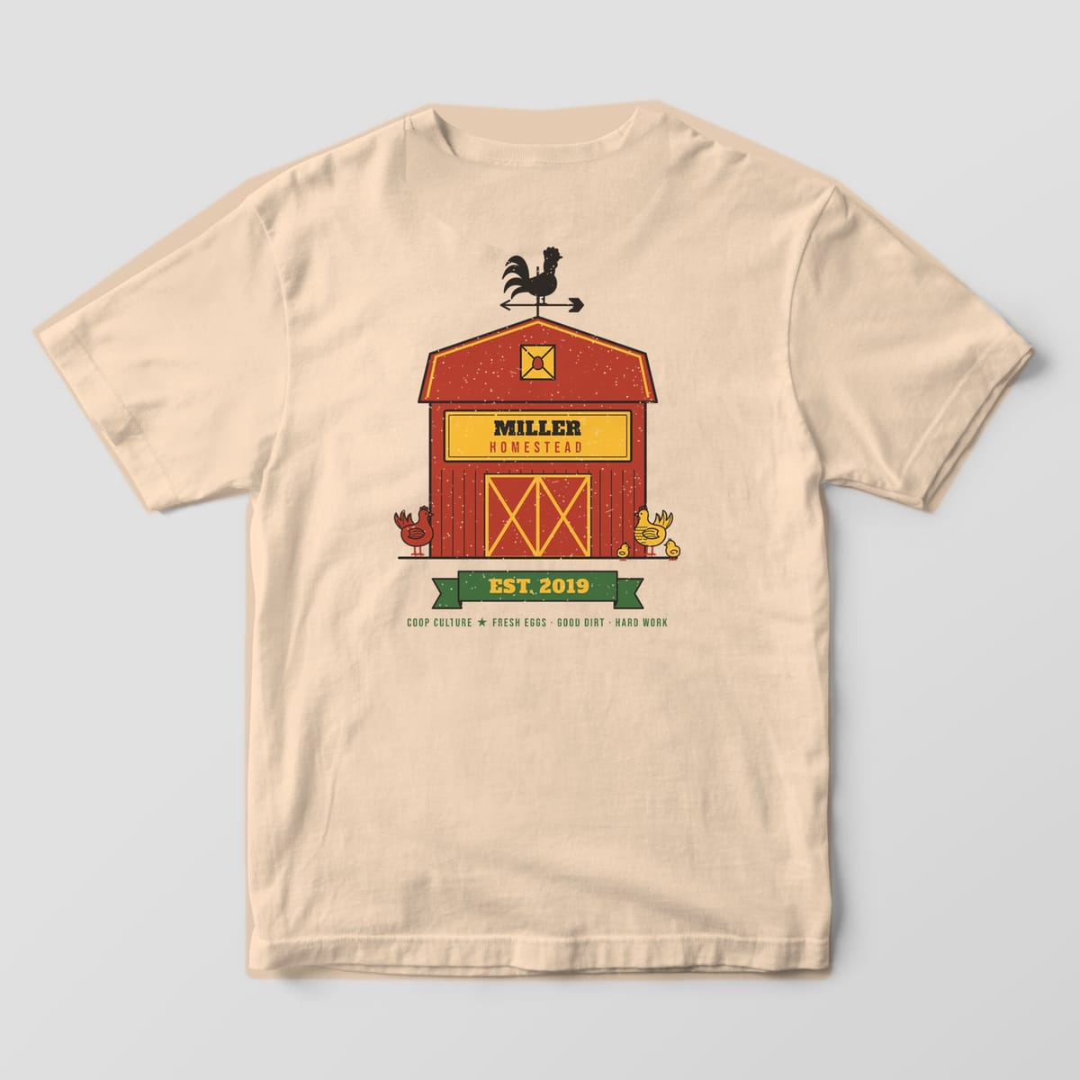 Back of an ivory Comfort Colors 1717 tee with a personalized red barn reading Miller Homestead and an Est. 2019 green ribbon.