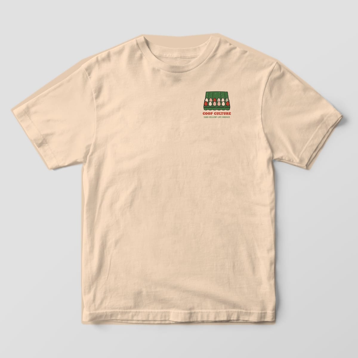 Front of an ivory Comfort Colors 1717 tee with a small egg carton icon and red Coop Culture text on the left chest.