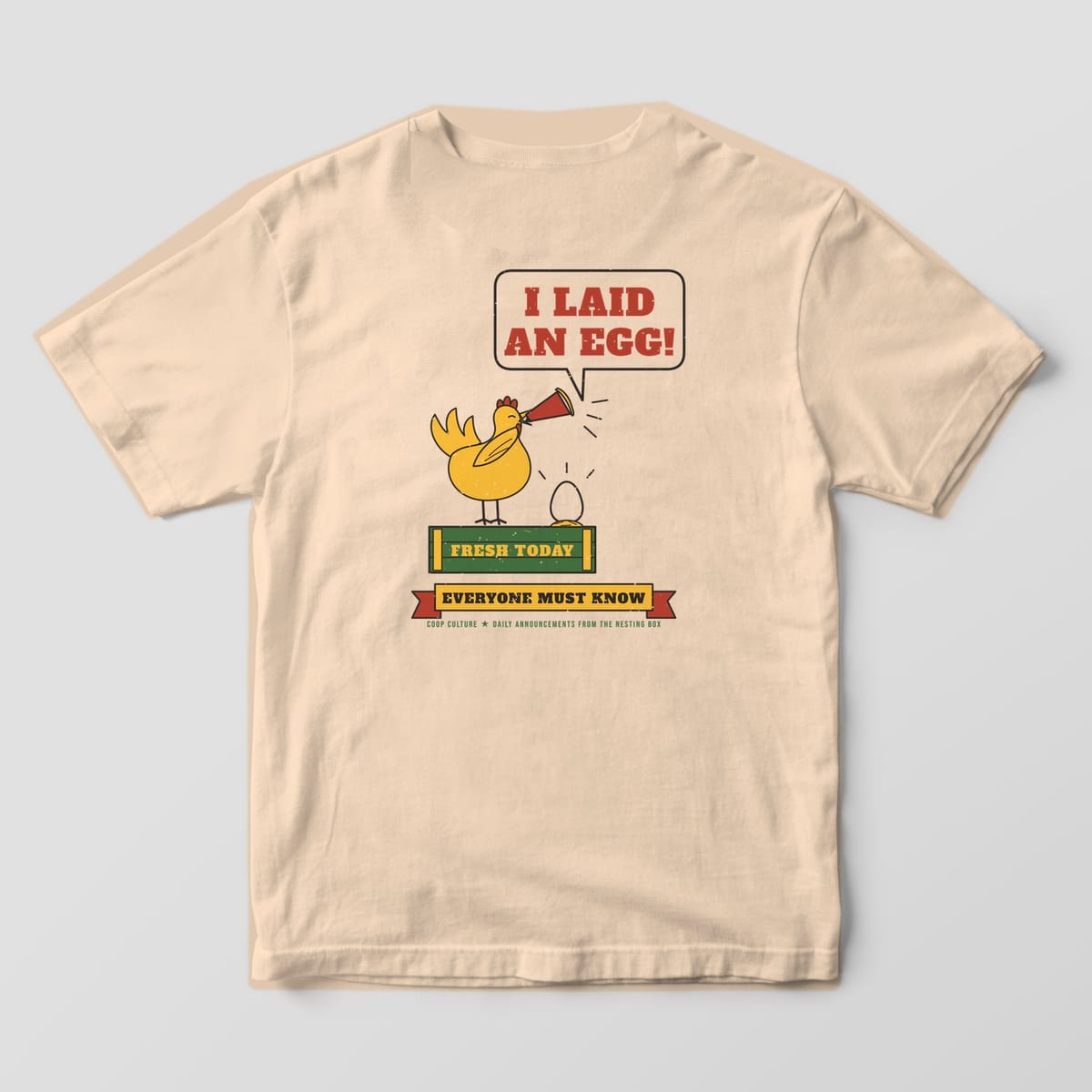 Back of an ivory Comfort Colors 1717 tee with a yellow hen on a crate shouting I Laid An Egg through a red megaphone above an Everyone Must Know banner.