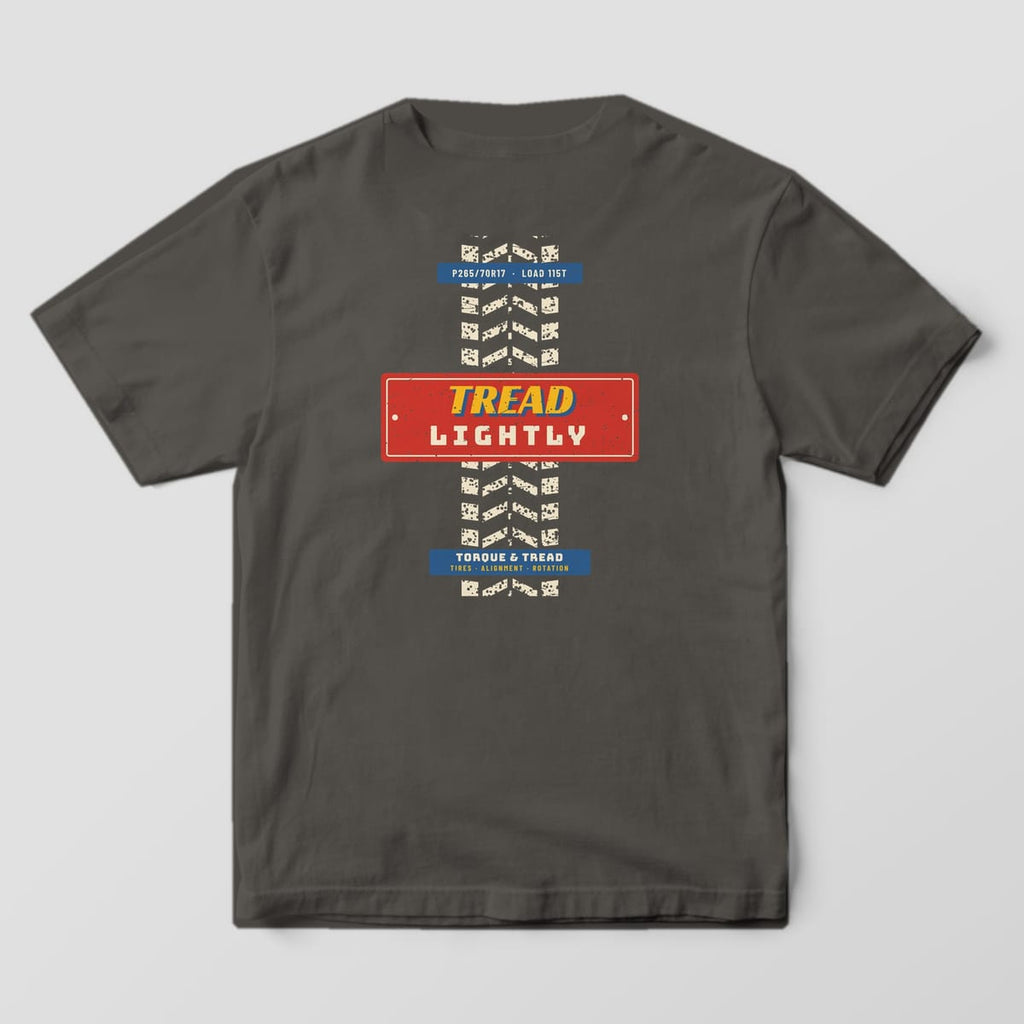 Back of a Pepper Comfort Colors 1717 tee with the cream worn tire tread track running down the back, crossed by a red plate reading Tread Lightly.