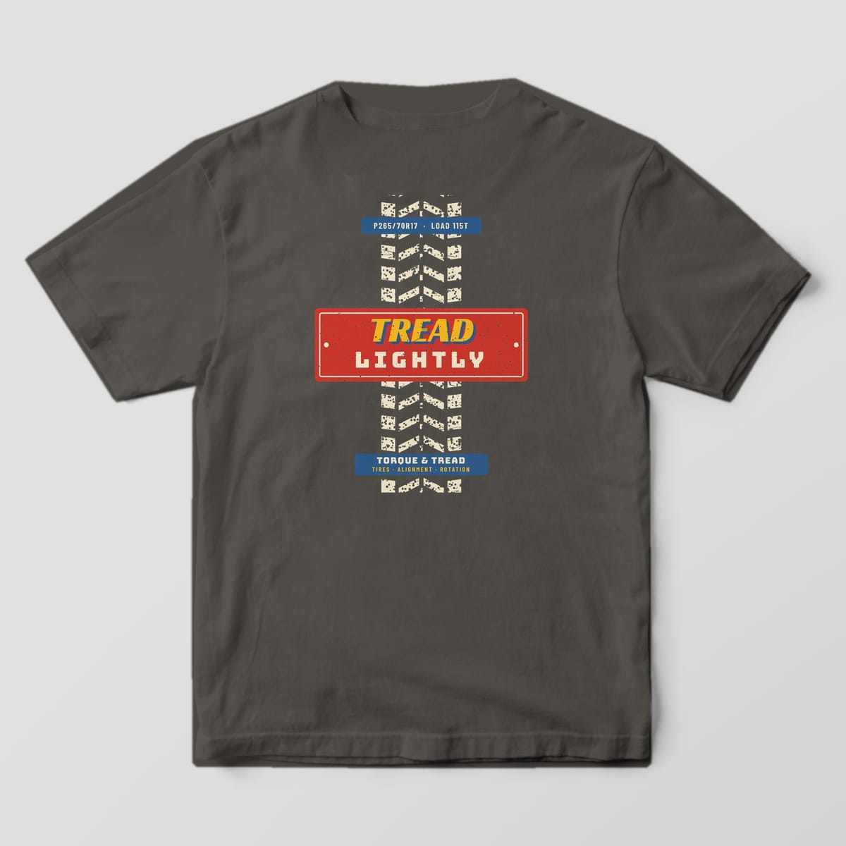 Back of a Pepper Comfort Colors 1717 tee with the cream worn tire tread track running down the back, crossed by a red plate reading Tread Lightly.