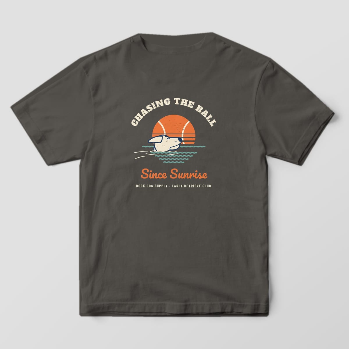 Back of a pepper Comfort Colors tee with an orange tennis-ball sun, teal waves, a swimming yellow lab and Since Sunrise script