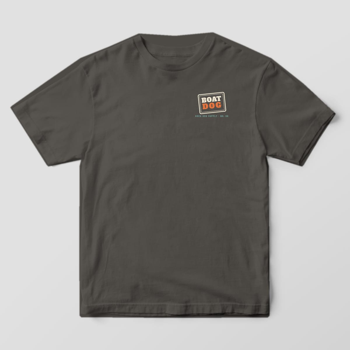 Front of a pepper Comfort Colors tee with a small cream and orange Boat Dog stamp on the left chest