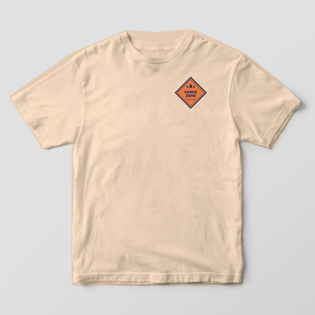 Front of an ivory Comfort Colors tee with a small orange Shake Zone caution diamond on the left chest