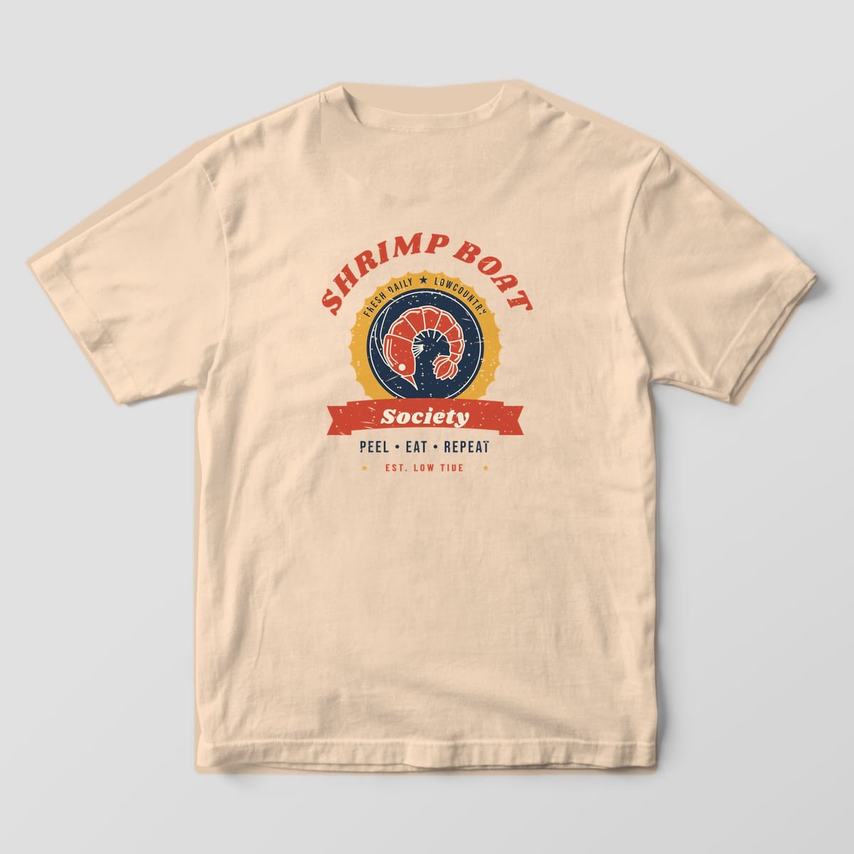 Back of an Ivory Comfort Colors 1717 tee with a red, gold and navy shrimp badge, SHRIMP BOAT arched above, a red Society banner and PEEL EAT REPEAT below.