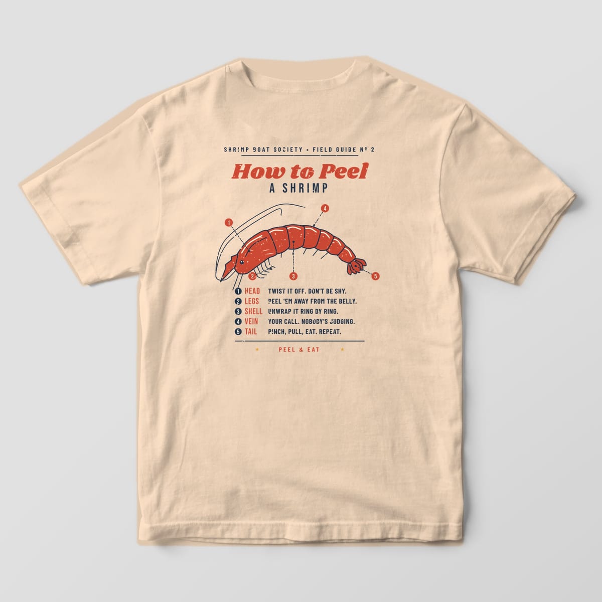 Back of an Ivory Comfort Colors 1717 tee with a red shrimp diagram, five numbered callouts and five peeling steps under the title How to Peel a Shrimp.