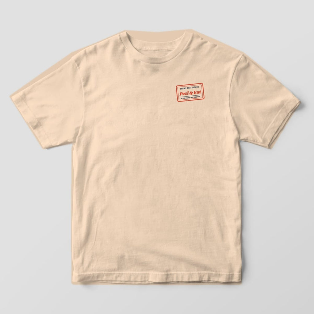 Front of an Ivory Comfort Colors 1717 tee with a small tilted red rubber-stamp box reading Peel and Eat on the left chest.