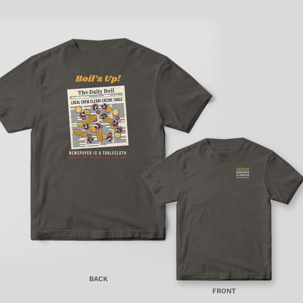 Pepper Comfort Colors tee shown back and front: an overhead shrimp boil spread on newspaper on the back and a small newspaper masthead text design on the left chest.