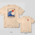 Ivory Comfort Colors tee shown back and front: framed blue great wave with red sun and FLOW on the back, small red TAP seal on the left chest.