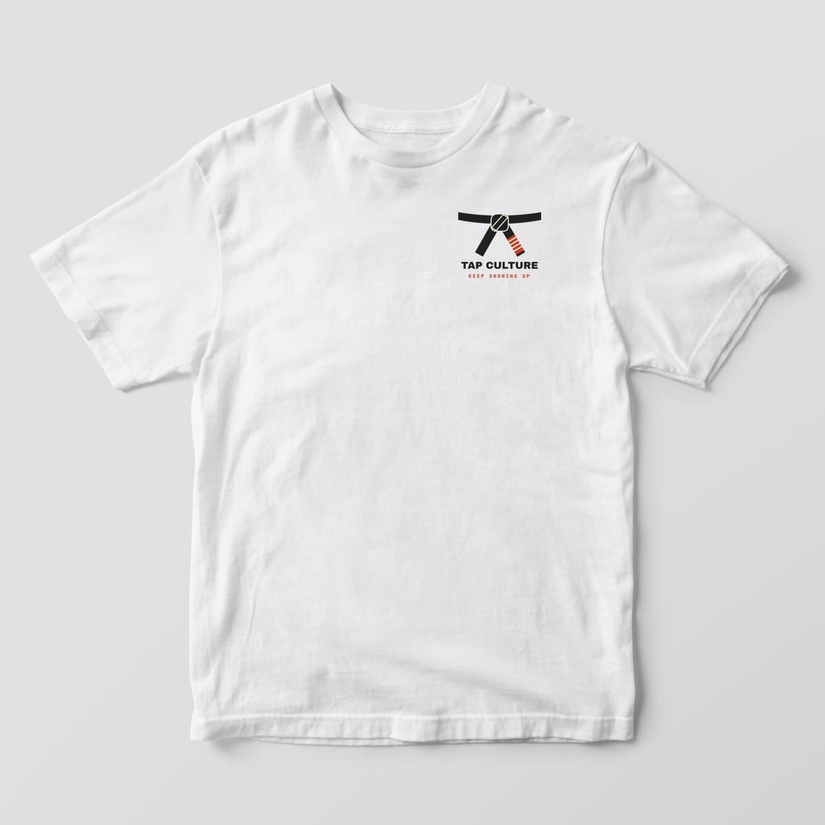 Front of a white Comfort Colors 1717 tee with a small black belt knot and TAP CULTURE on the left chest.