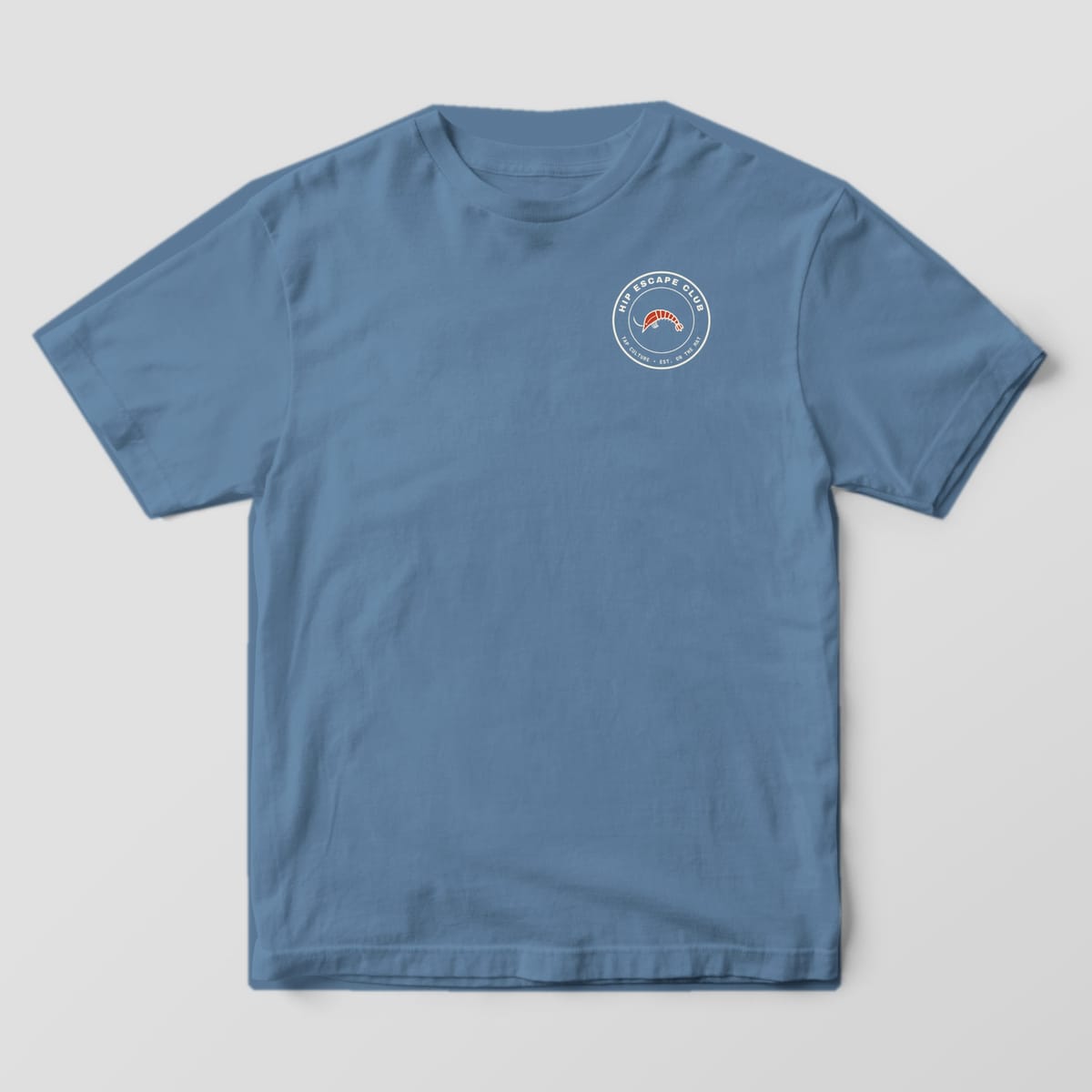 Front of a blue jean Comfort Colors 1717 tee with a small round HIP ESCAPE CLUB shrimp badge on the left chest.