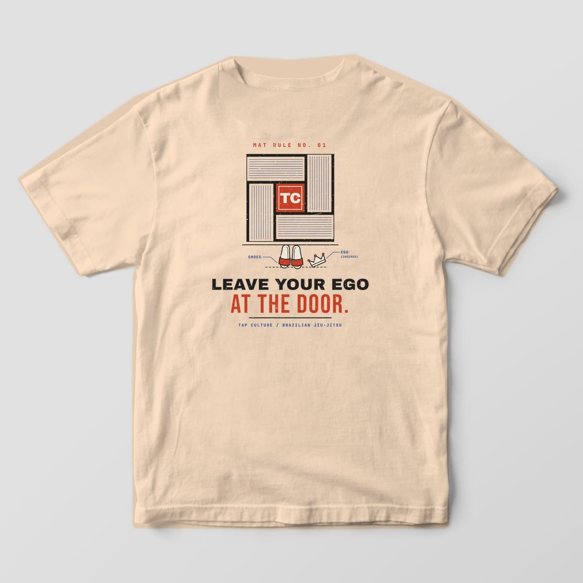 Back of an ivory Comfort Colors 1717 tee with a tatami mat drawing, red TC seal, slides and crown, and Leave Your Ego at the Door text.