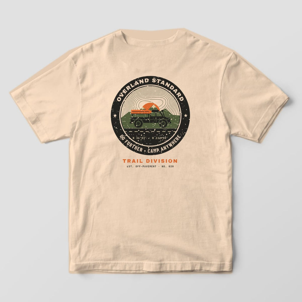 Back of a Ivory Comfort Colors 1717 tee with a black, orange and olive badge reading Overland Standard, Go Further, Camp Anywhere around a rooftop-tent truck.