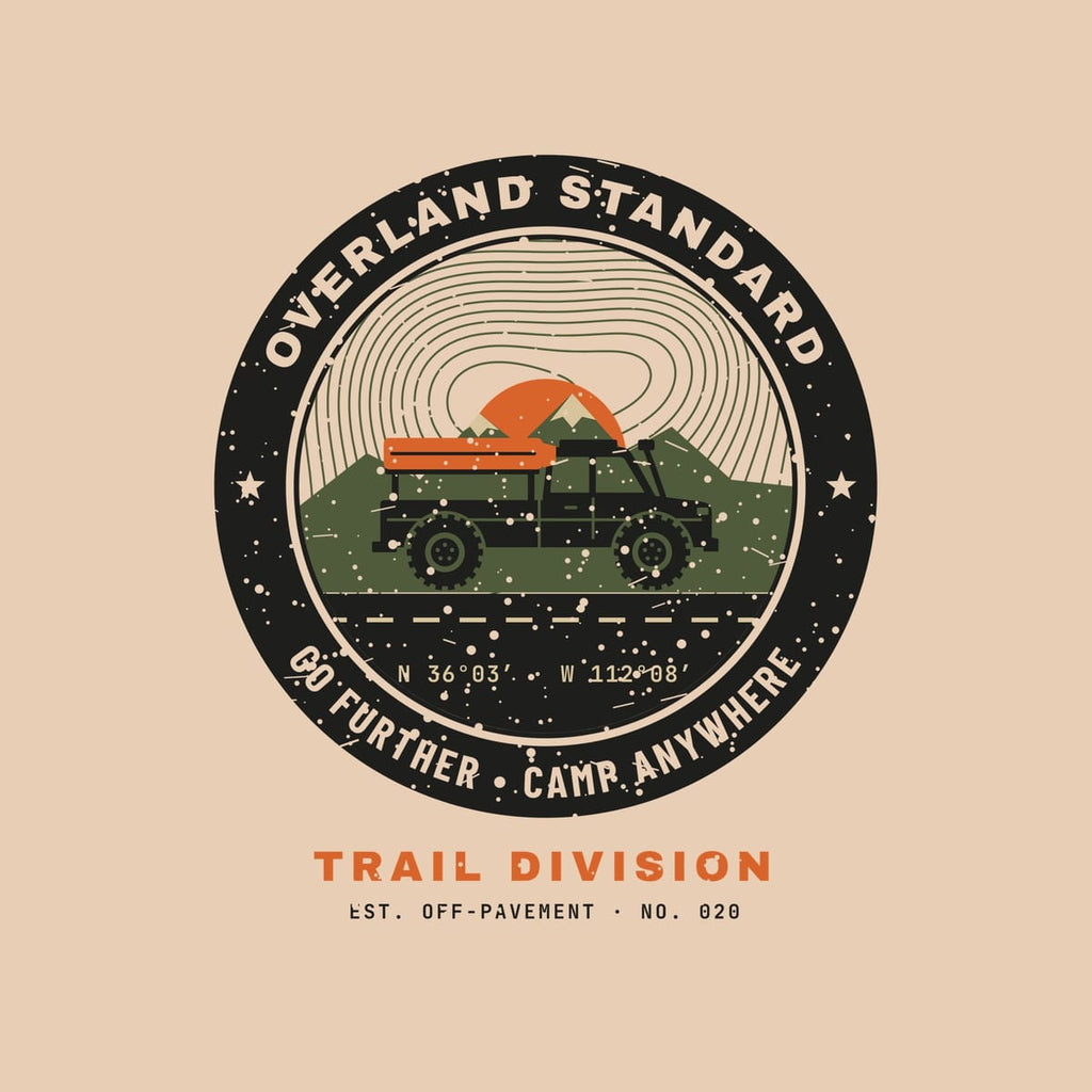 Close-up of the topo badge print: contour lines, orange sun, olive ridge, black truck with rooftop tent and speckled vintage texture.
