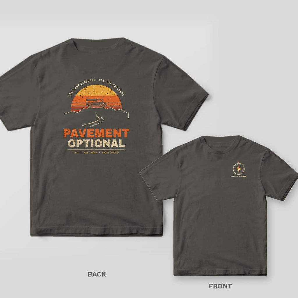 Pepper Comfort Colors tee shown back and front: a retro striped sunset with a truck on a ridge and Pavement Optional on the back, a small compass rose on the chest.