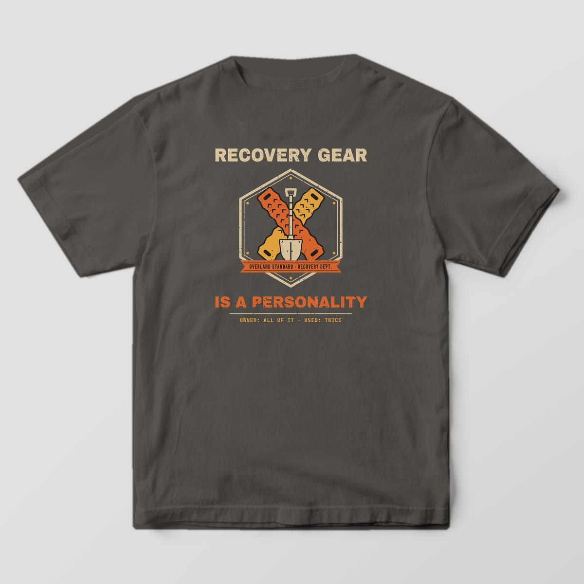 Back of a Pepper Comfort Colors 1717 tee with crossed orange and gold traction boards behind a shovel in a hex badge and the words Recovery Gear Is a Personality.