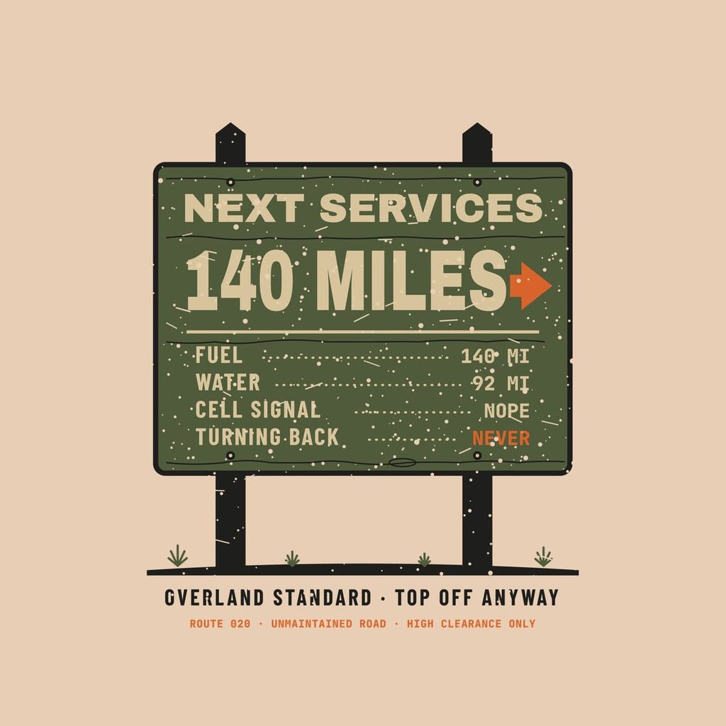 Close-up of the trailhead sign print: sand routed lettering on olive wood grain, orange arrow, bolts, black posts and sagebrush.