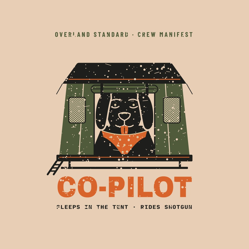 Close-up of the back print artwork on a ivory background: a black lab in an orange bandana looking out of an olive rooftop tent door above the word Co-Pilot