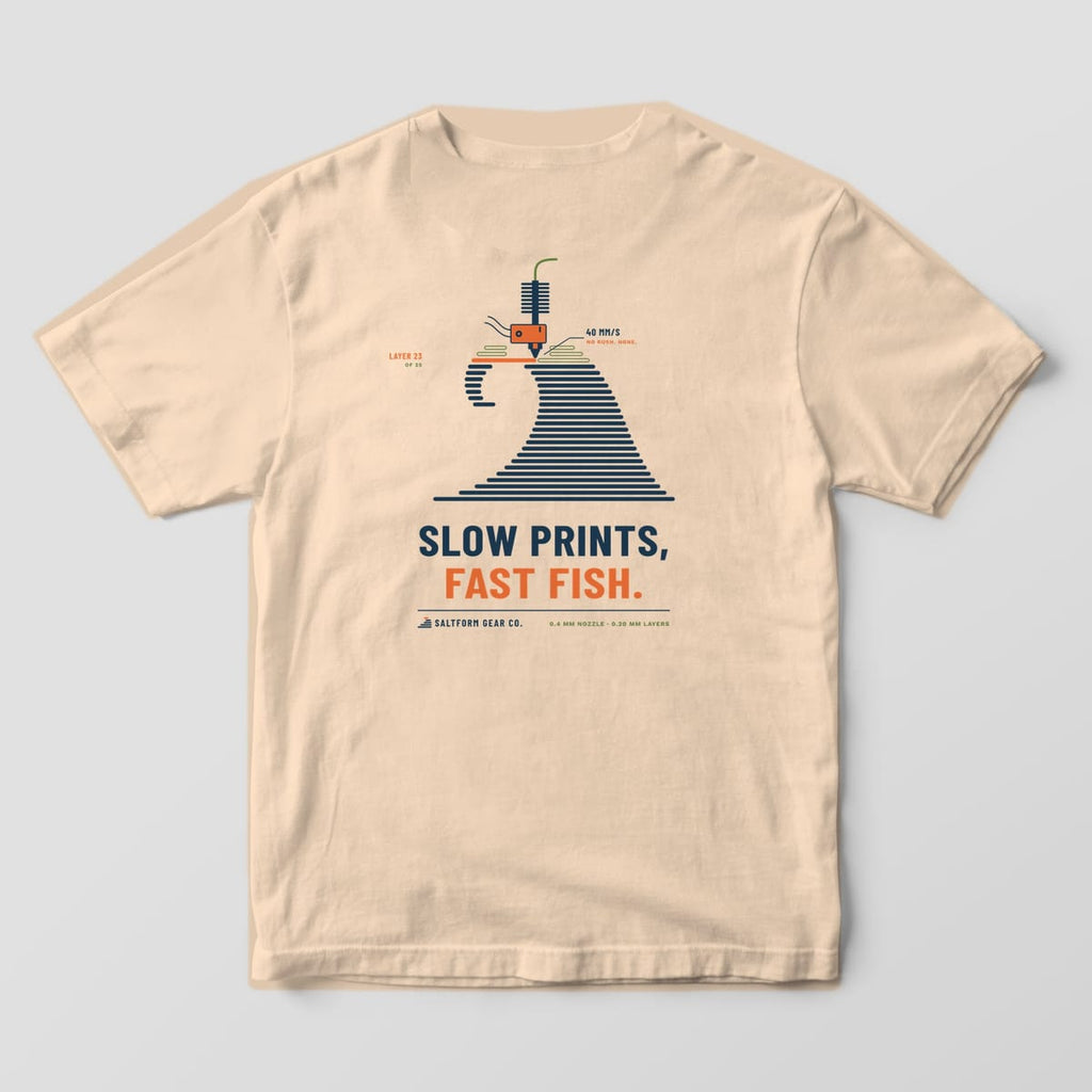 Back of an ivory Comfort Colors 1717 tee with a curling navy wave made of print layers, a hotend nozzle and SLOW PRINTS, FAST FISH.