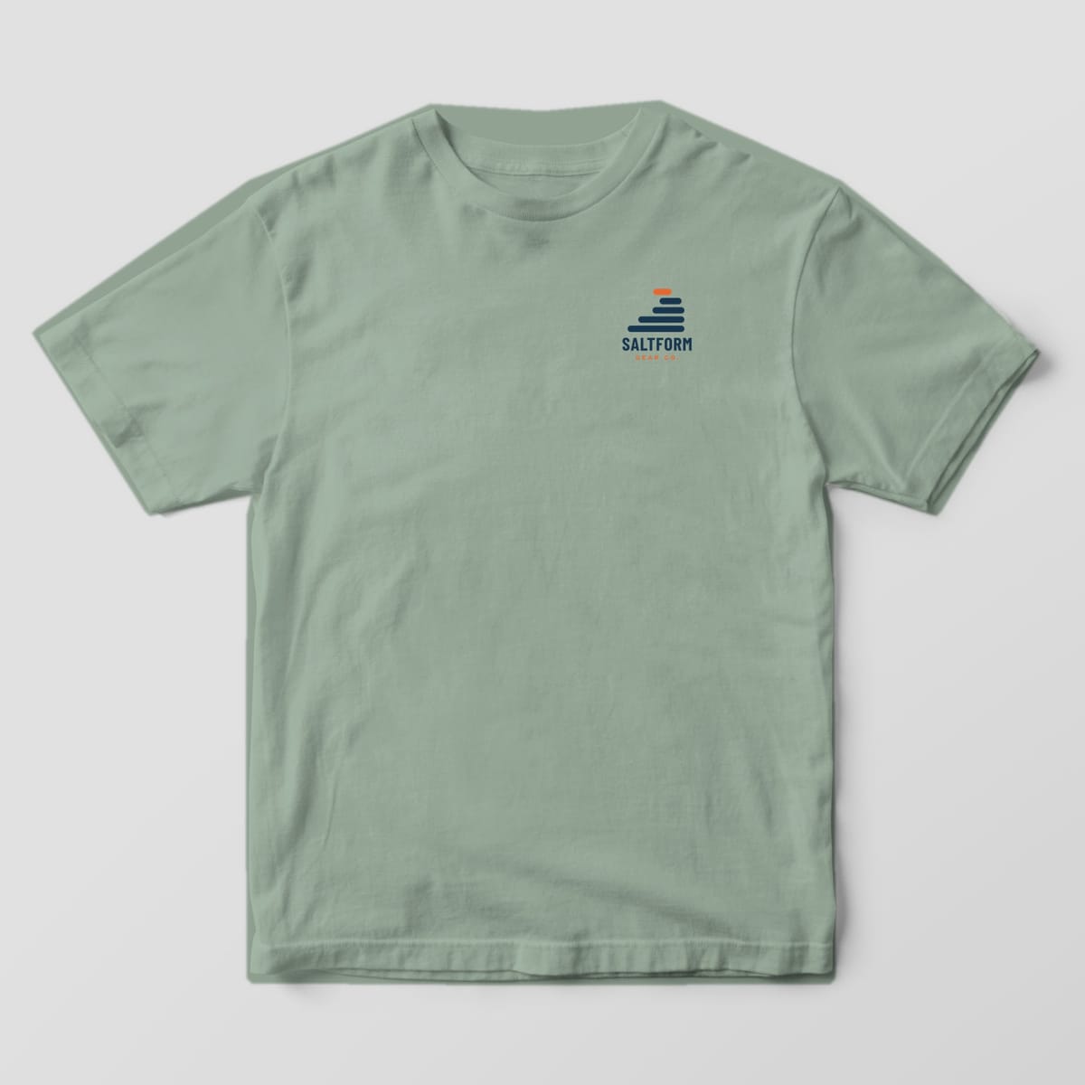 Front of a bay green Comfort Colors 1717 tee with a small navy and orange layer-wave logo and SALTFORM on the left chest.