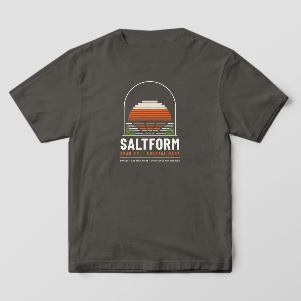 Back of a pepper gray Comfort Colors 1717 tee with a sand and orange layer-line sunset over water and marsh grass inside an arch.
