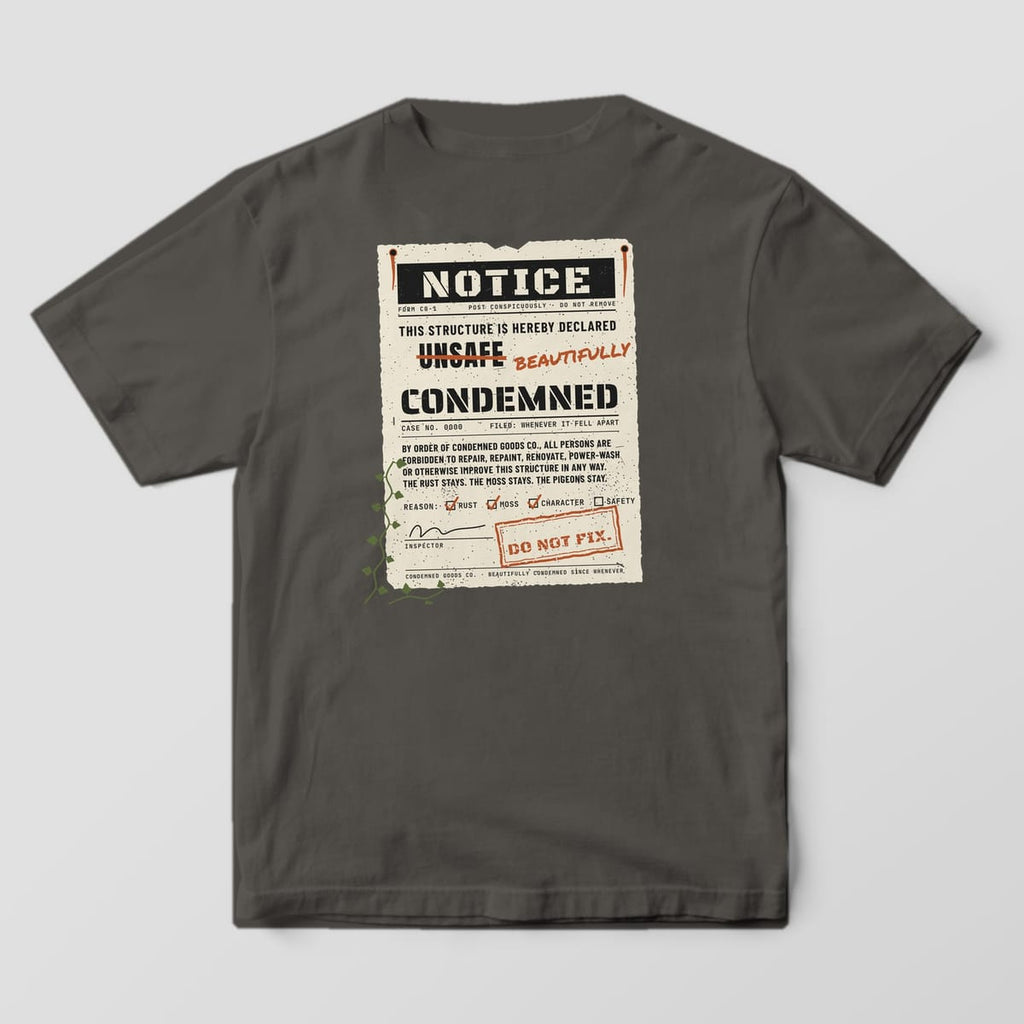Back of a pepper Comfort Colors 1717 tee with a large nailed-up notice print reading This Structure Is Hereby Declared Beautifully Condemned.