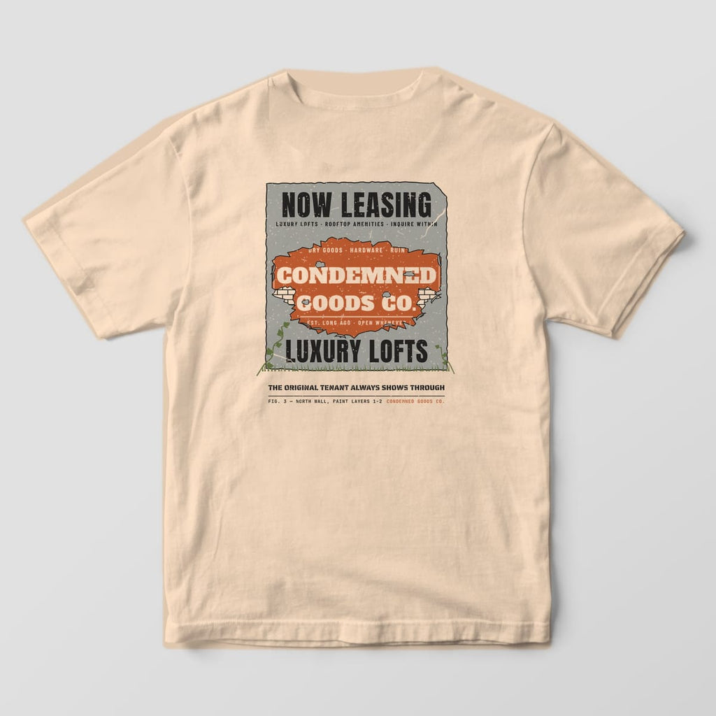 Back of an ivory Comfort Colors 1717 tee with a peeling-paint wall print revealing an old rust ghost sign under a Luxury Lofts ad.