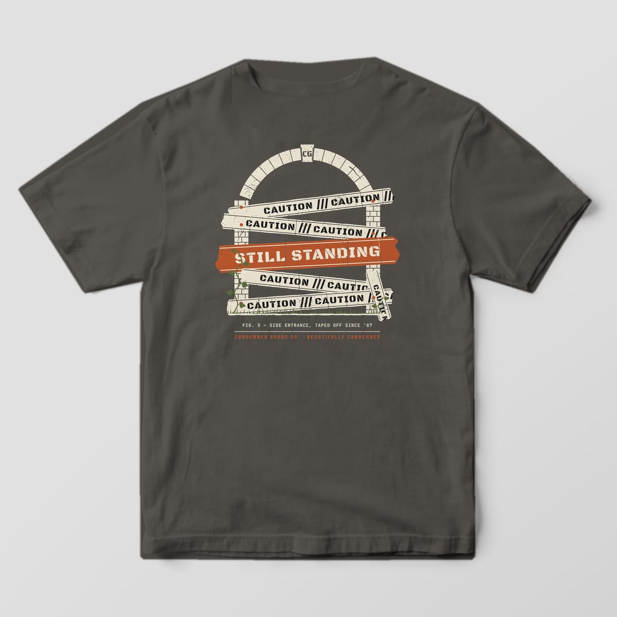 Back of a pepper Comfort Colors 1717 tee with cream caution tape strips across a brick arch and a rust Still Standing band.
