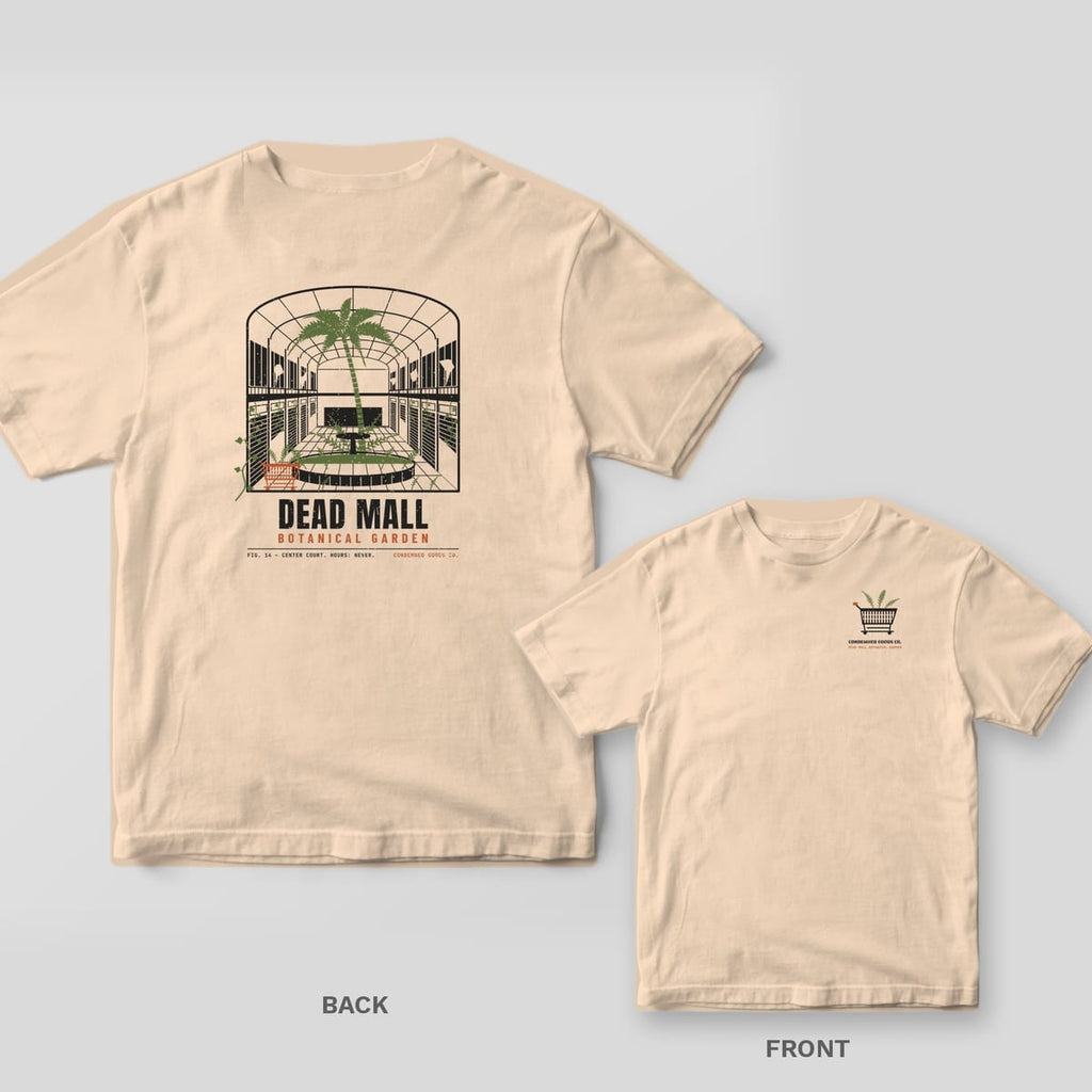 Ivory tee shown back and front: back has an abandoned mall atrium with a palm tree growing out of the fountain under the words Dead Mall Botanical Garden; front has a small shopping cart with ferns growing from it.