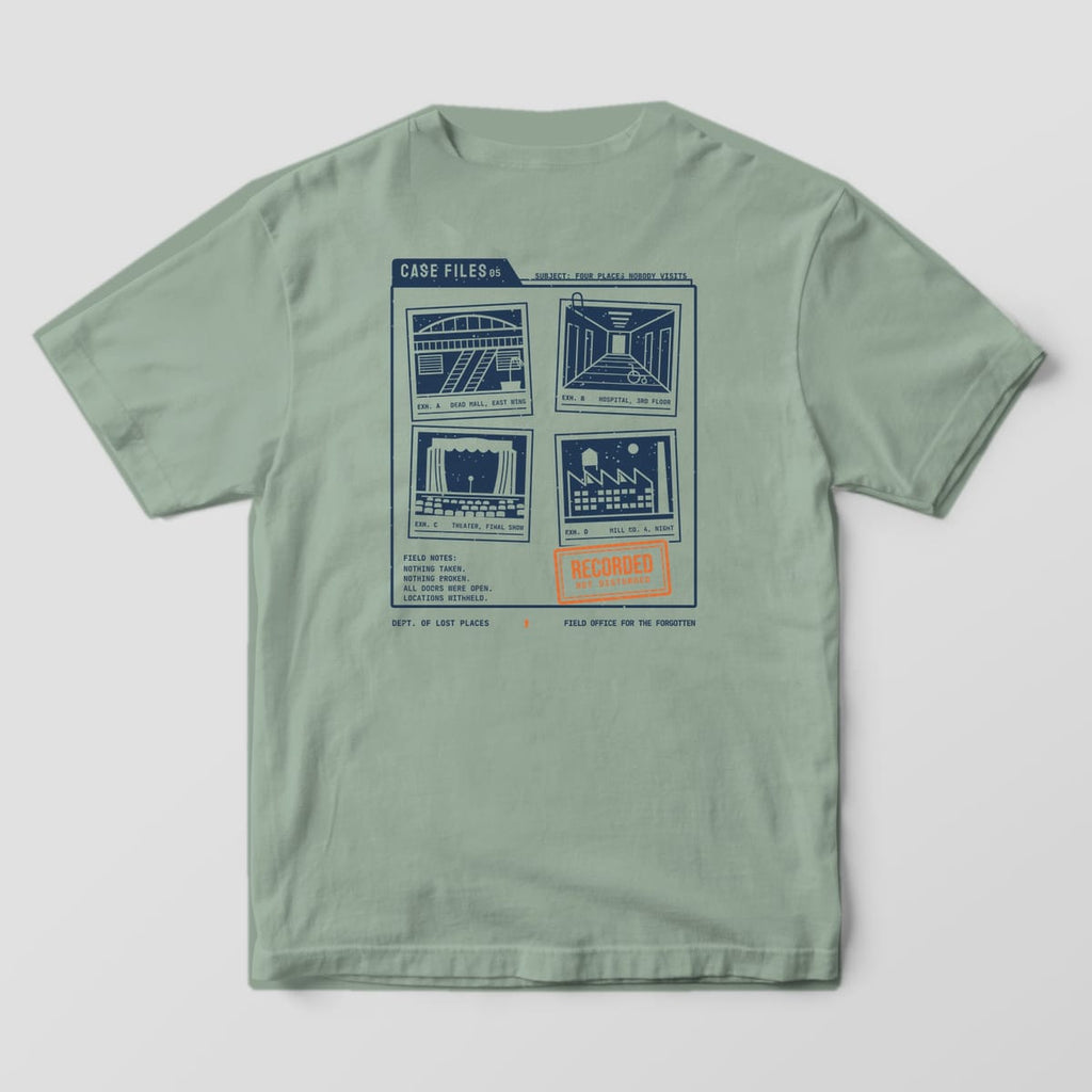 Back of a Bay Comfort Colors 1717 tee printed with a navy case folder holding four photos of a dead mall, hospital hallway, abandoned theater and old mill, with typed field notes and an orange Recorded, Not Disturbed stamp.