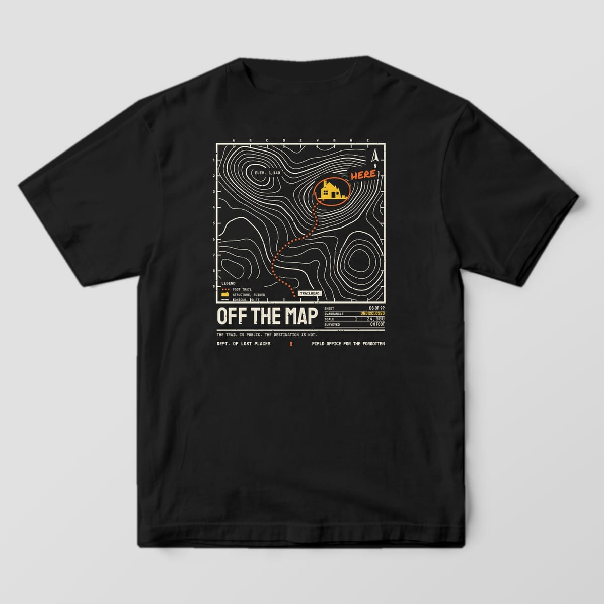 Back of a Black Comfort Colors 1717 tee printed with a cream topographic contour map with an orange dotted trail leading to a yellow ruined house circled and marked Here, above the title Off the Map.