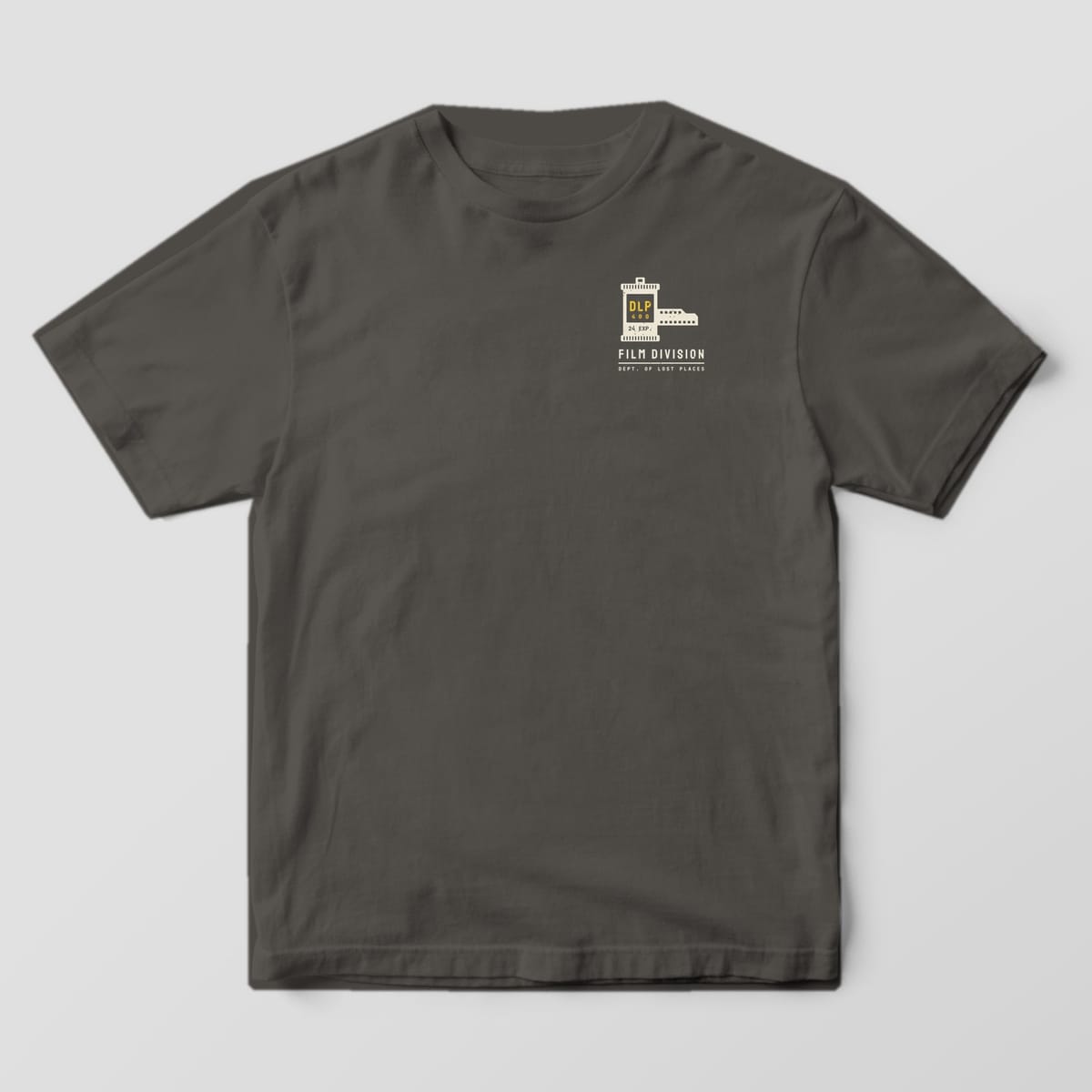 Front of a Pepper Comfort Colors 1717 tee with a small cream film canister labeled DLP 400 with film leader above the words Film Division on the left chest.