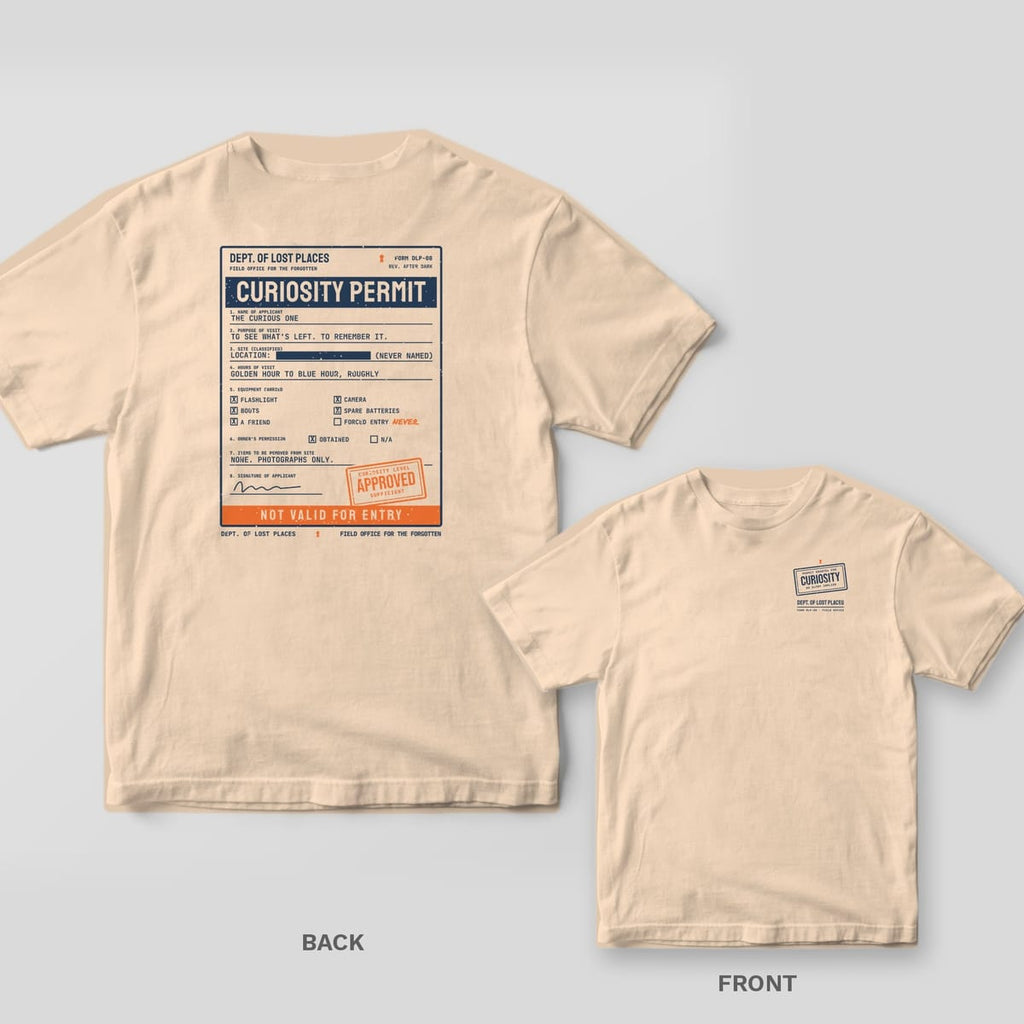 Ivory Comfort Colors tee shown back and front: the back has a navy typewritten Curiosity Permit form with an orange Approved stamp and Not Valid for Entry strip; the chest has a small Curiosity rubber stamp.