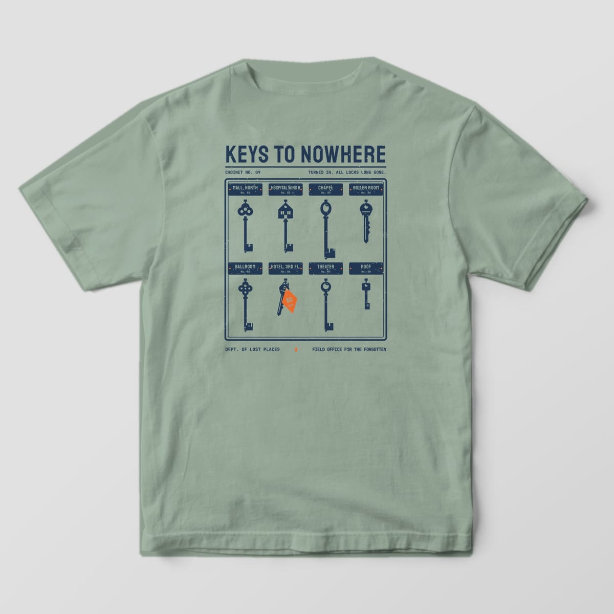 Back of a Bay Comfort Colors 1717 tee printed with a navy key cabinet holding eight vintage skeleton and hotel keys above name plates for places like Chapel, Ballroom and Roof, under the title Keys to Nowhere.