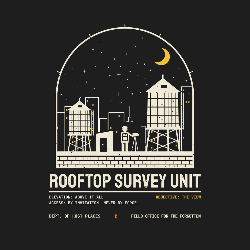 Back print artwork close-up: a cream arched night scene of a city rooftop with two water towers, an explorer at a tripod, lit skyline windows and a yellow crescent moon above Rooftop Survey Unit, lightly speckled.