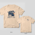 Ivory Comfort Colors tee shown back and front: the back has a navy lost and found box with a cassette, roller skate, tickets and keys above Logged, Not Taken; the chest has a small file folder.